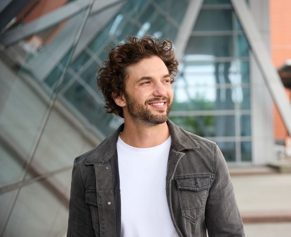 Person standing outside near a modern building.