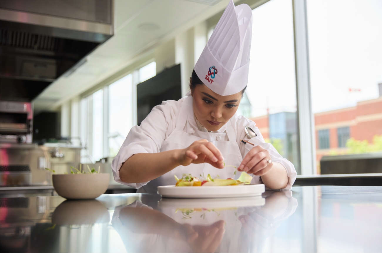 A hospitality student plates a dish.