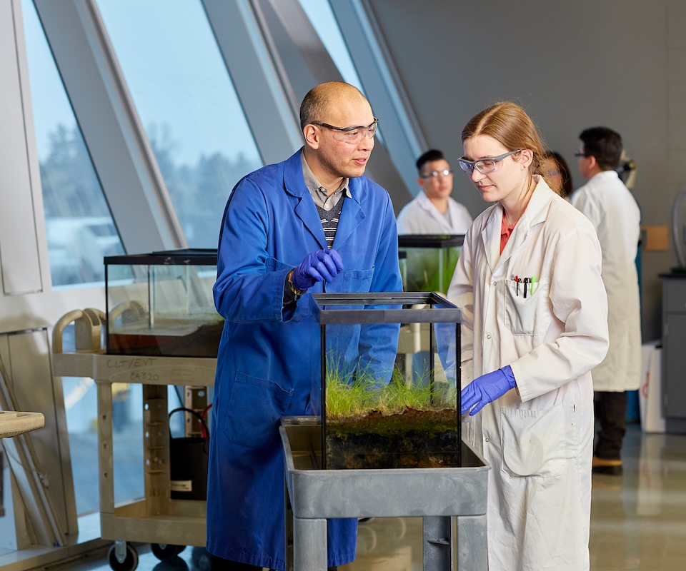 An instructor and student working with a soil and water sample in the lab.
