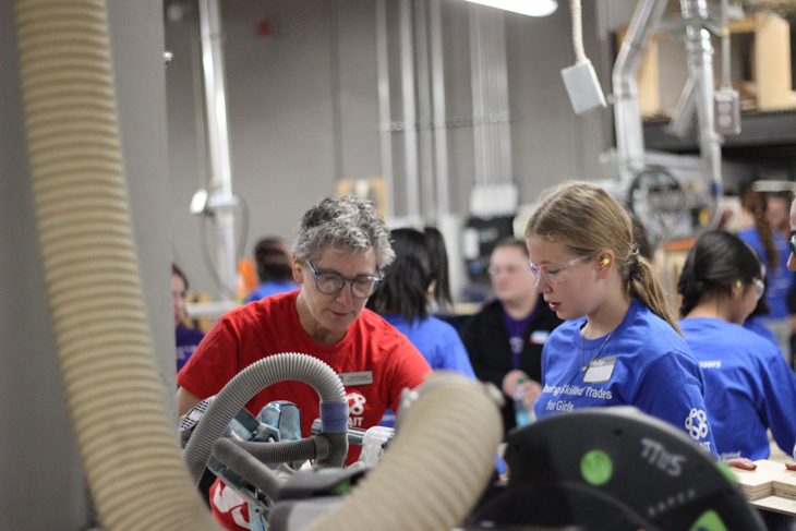 SAIT carpentry instructor teaches a student how to use a table saw in a wood trades lab